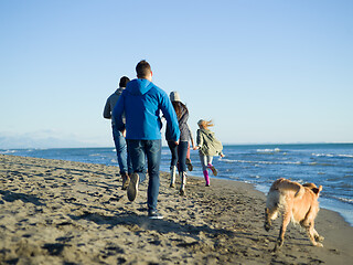 Image showing Group of friends running on beach during autumn day