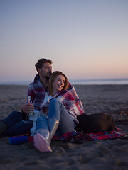 Image showing Loving Young Couple Sitting On The Beach beside Campfire drinkin