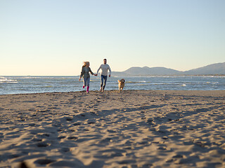 Image showing couple with dog having fun on beach on autmun day