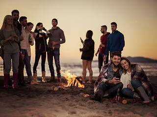 Image showing Couple enjoying bonfire with friends on beach