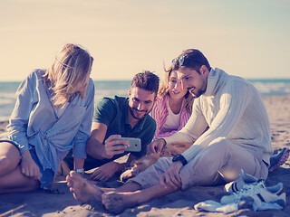 Image showing Group of friends having fun on beach during autumn day