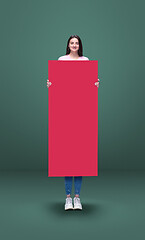 Image showing Tall high woman and long pink banner isolated on green studio background. Unusual delighted and long