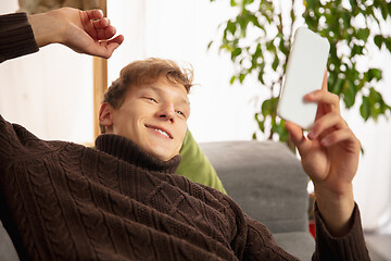 Image showing Man reading message, greetings for New Year and Christmas 2021 from friends or family with his cellphone