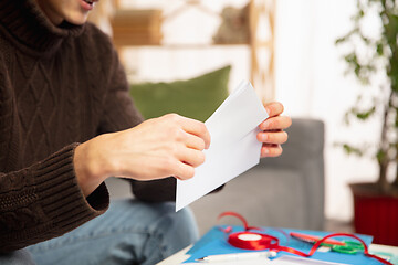 Image showing Man opening, recieving greeting card for New Year and Christmas 2021 from friends or family