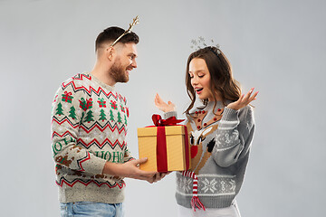 Image showing happy couple in christmas sweaters with gift box