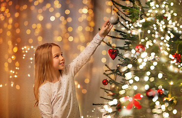 Image showing happy girl in red dress decorating christmas tree