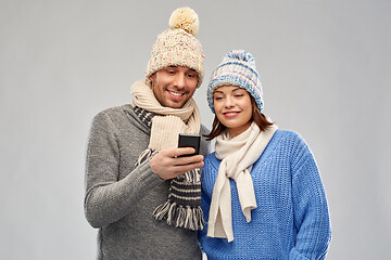 Image showing happy couple in winter clothes with smartphone