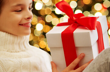 Image showing happy girl with christmas gift over festive lights