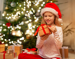 Image showing smiling girl in santa hat with christmas gift