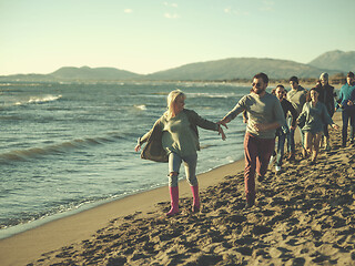 Image showing Group of friends running on beach during autumn day