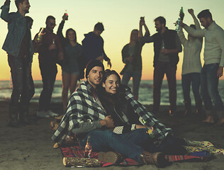 Image showing Couple enjoying with friends at sunset on the beach