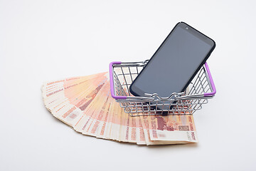 Image showing Against the background of five thousandth bills is a grocery basket with a cell phone