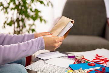 Image showing Woman opening, recieving greeting card for New Year and Christmas 2021 from friends or family