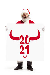 Image showing Stylish Santa Claus in traditional costume with 2021 big banner in hands on white studio background