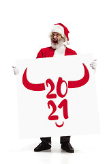 Image showing Stylish Santa Claus in traditional costume with 2021 big banner in hands on white studio background