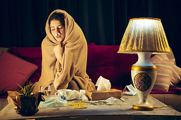 Image showing Woman wrapped in a plaid looks sick, ill, sneezing and coughing sitting at home indoors