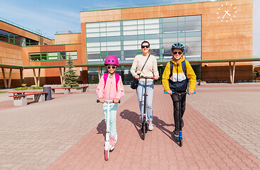 Image showing happy school children with mother riding scooters