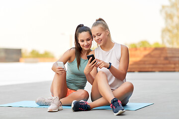 Image showing sporty women or friends with smartphone on rooftop