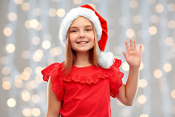 Image showing smiling girl in santa helper hat waving hand