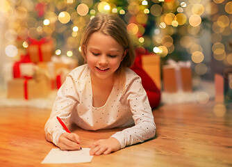 Image showing smiling girl writing christmas wish list at home