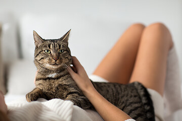 Image showing happy young woman with cat lying in bed at home