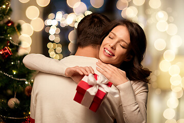 Image showing happy couple with christmas gift hugging at home