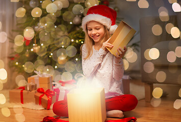 Image showing smiling girl in santa hat opening christmas gift