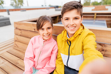 Image showing children sitting on street bench and taking selfie