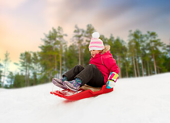 Image showing happy little girl sliding down on sled in winter