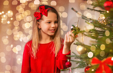 Image showing happy girl in red decorating christmas tree