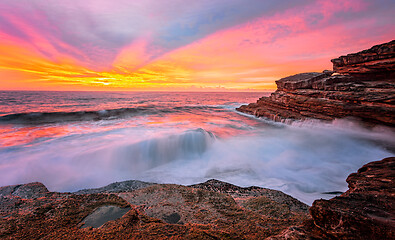 Image showing Sunrise sun rays light up the sky and reflect in the ocean and r