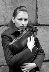 Image showing woman in black holding portfolio near brick wall