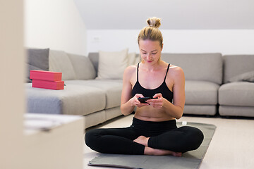 Image showing Beautiful blonde woman doing home workout indoors. Woman practice yoga at home. Fit girl using workout tutorials for healthy active lifestyle. Woman using quarantine for home workouts.