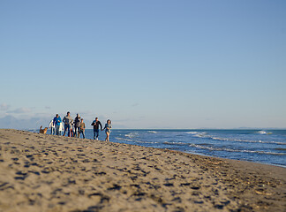 Image showing Group of friends running on beach during autumn day