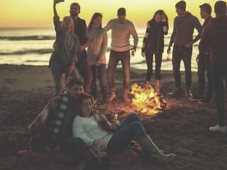 Image showing Couple enjoying with friends at sunset on the beach