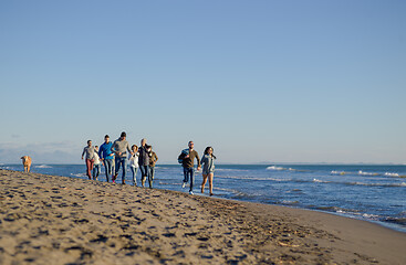 Image showing Group of friends running on beach during autumn day