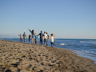 Image showing Group of friends running on beach during autumn day