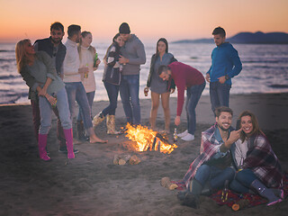 Image showing Couple enjoying bonfire with friends on beach