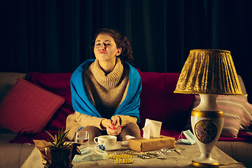 Image showing Woman wrapped in a plaid looks sick, ill, sneezing and coughing sitting at home indoors