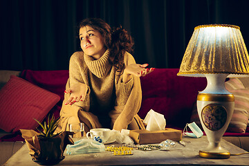 Image showing Woman wrapped in a plaid looks sick, ill, sneezing and coughing sitting at home indoors