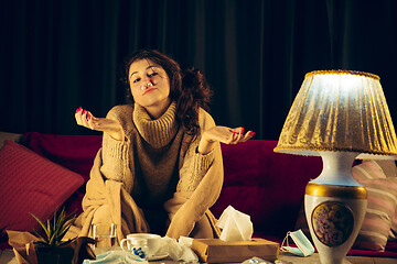 Image showing Woman wrapped in a plaid looks sick, ill, sneezing and coughing sitting at home indoors