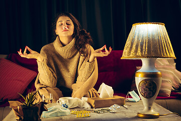 Image showing Woman wrapped in a plaid looks sick, ill, sneezing and coughing sitting at home indoors