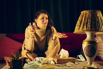 Image showing Woman wrapped in a plaid looks sick, ill, sneezing and coughing sitting at home indoors