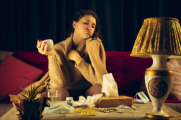 Image showing Woman wrapped in a plaid looks sick, ill, sneezing and coughing sitting at home indoors