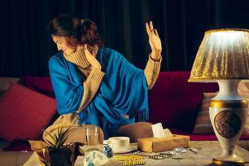 Image showing Woman wrapped in a plaid looks sick, ill, sneezing and coughing sitting at home indoors