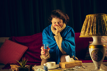 Image showing Woman wrapped in a plaid looks sick, ill, sneezing and coughing sitting at home indoors