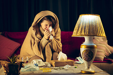 Image showing Woman wrapped in a plaid looks sick, ill, sneezing and coughing sitting at home indoors