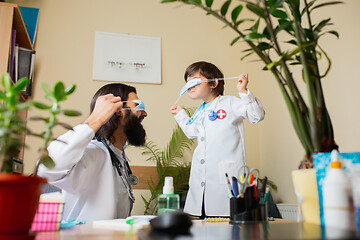 Image showing Paediatrician doctor examining a child while wearing face mask in comfortabe medical office