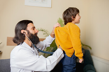 Image showing Paediatrician doctor examining a child in comfortabe medical office