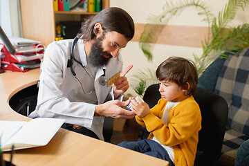 Image showing Paediatrician doctor examining a child in comfortabe medical office